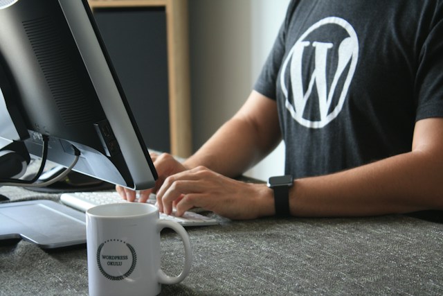 Man wearing a t-shirt with WordPress logo working on a computer